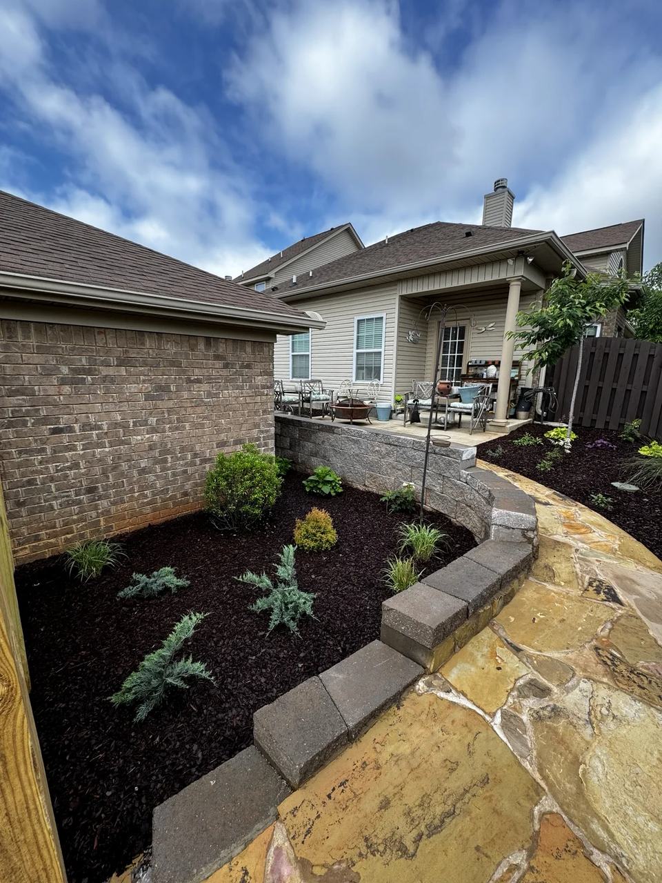 Curving stone walkway beside a retaining wall and a newly installed landscape