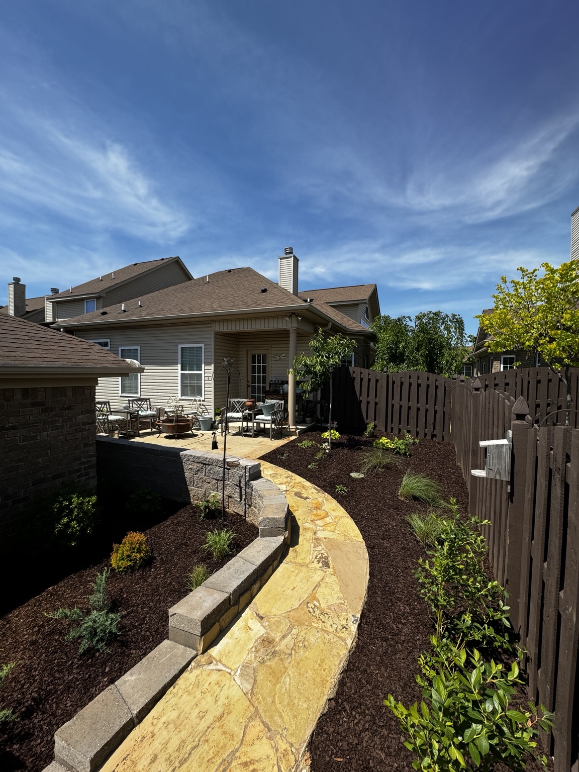 Finished courtyard with curved stone path, retaining walls, planting and dark mulch
